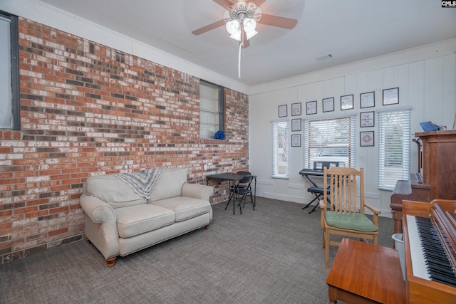 carpeted living room featuring ceiling fan and brick wall