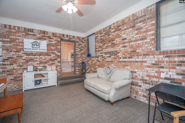 living area with a textured ceiling, carpet flooring, ceiling fan, and brick wall