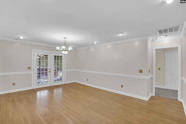 empty room featuring an inviting chandelier, light wood-type flooring, french doors, and crown molding