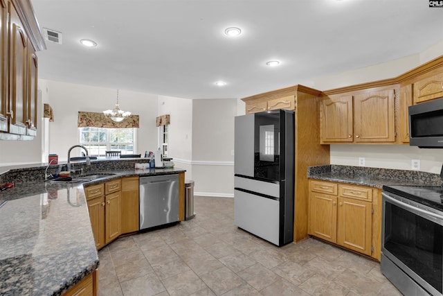 kitchen with stainless steel appliances, dark stone counters, a notable chandelier, hanging light fixtures, and sink