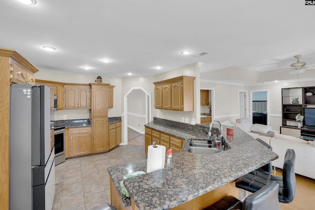 kitchen with stainless steel appliances, a kitchen bar, sink, and ceiling fan