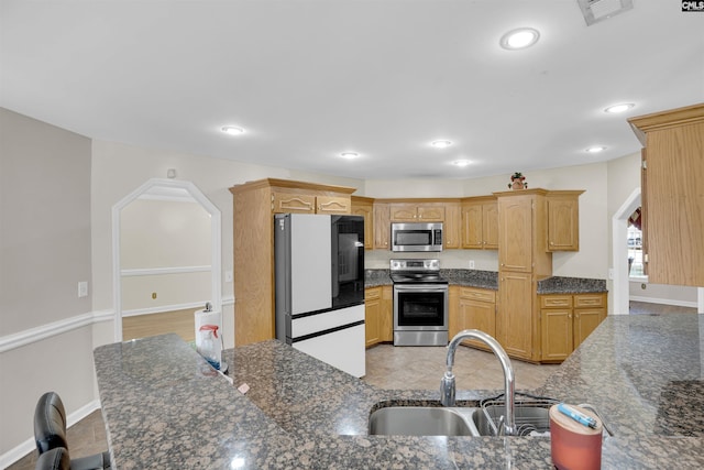 kitchen featuring appliances with stainless steel finishes, sink, and dark stone countertops