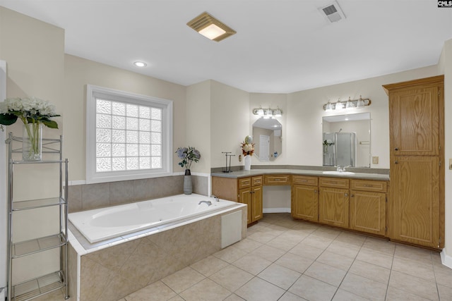 bathroom with vanity, tile patterned flooring, and tiled tub