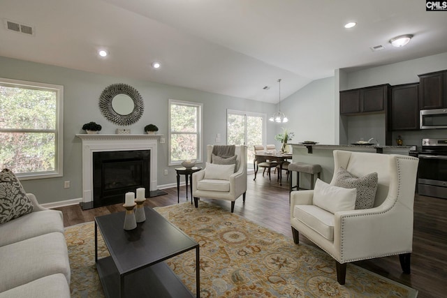 living room with a wealth of natural light, vaulted ceiling, and dark hardwood / wood-style flooring