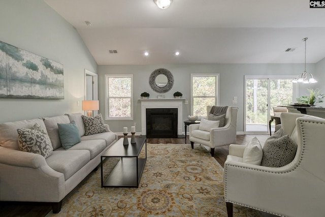 living room featuring hardwood / wood-style floors, lofted ceiling, and an inviting chandelier