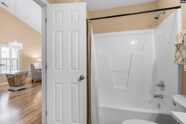 bathroom featuring shower / bathtub combination with curtain, hardwood / wood-style floors, a chandelier, toilet, and vaulted ceiling