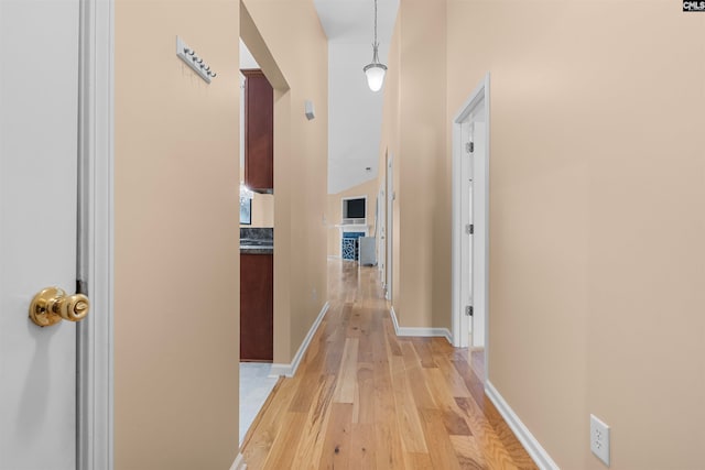 hallway featuring light wood-type flooring and a high ceiling