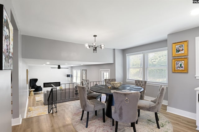 dining space with hardwood / wood-style floors and ceiling fan with notable chandelier