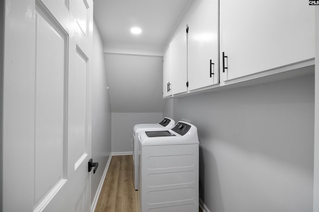 clothes washing area with cabinets, light hardwood / wood-style floors, and washer and clothes dryer