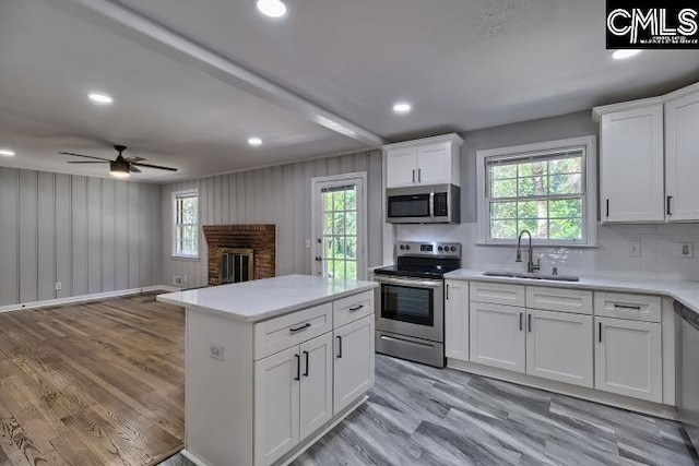 kitchen with stainless steel appliances, a sink, light countertops, a ceiling fan, and white cabinets