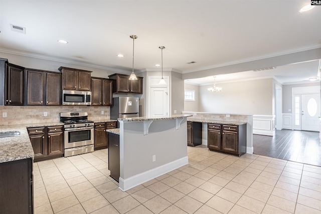 kitchen with a center island, appliances with stainless steel finishes, decorative light fixtures, and plenty of natural light