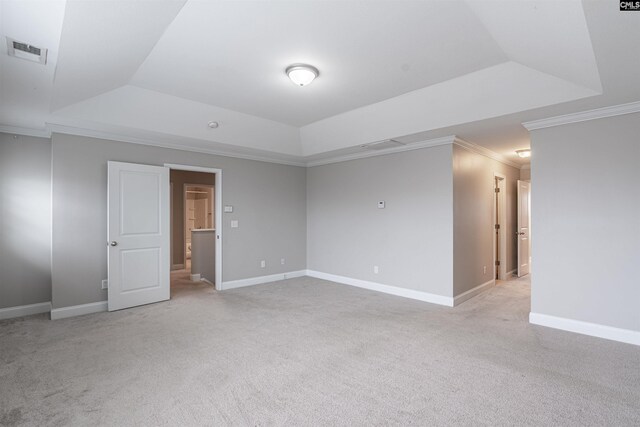 carpeted empty room with a tray ceiling and ornamental molding