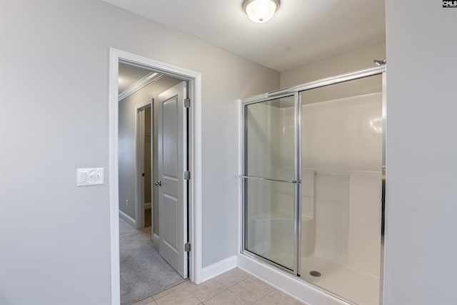 bathroom with a shower with door, tile patterned floors, and crown molding