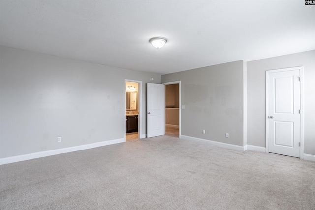 unfurnished bedroom with connected bathroom and light carpet