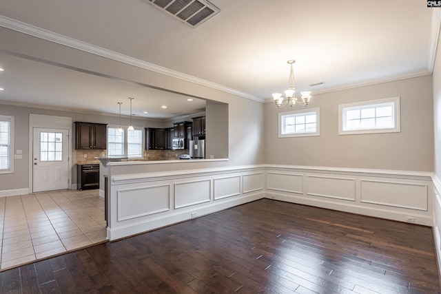 kitchen featuring dark brown cabinetry, a wealth of natural light, wood-type flooring, and decorative backsplash