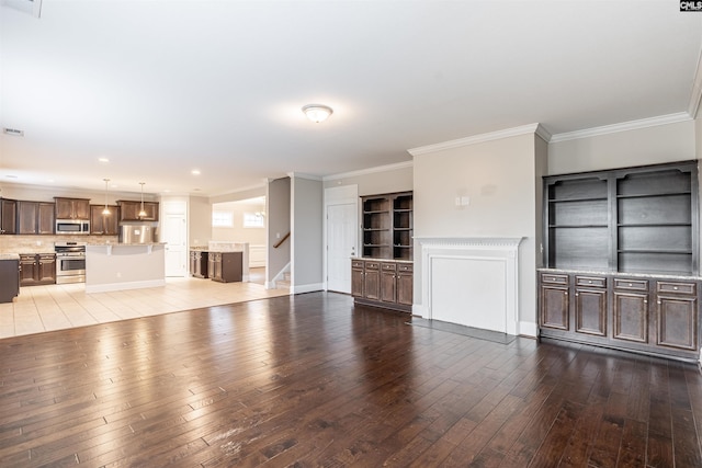 unfurnished living room featuring hardwood / wood-style flooring, built in features, and ornamental molding