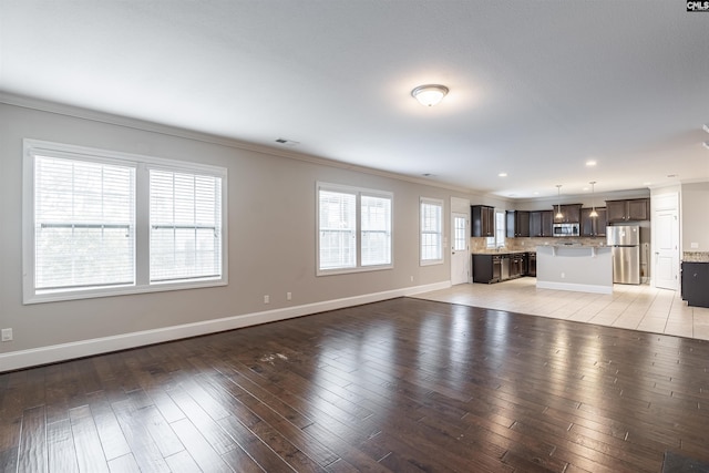 unfurnished living room with plenty of natural light, light hardwood / wood-style flooring, and crown molding