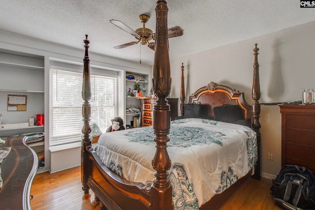 bedroom with a textured ceiling, wood-type flooring, and ceiling fan