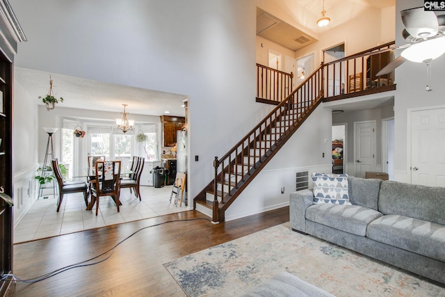 living room featuring light hardwood / wood-style floors, a chandelier, and a towering ceiling