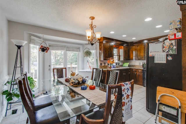 dining room with a chandelier, sink, light tile patterned flooring, and a textured ceiling