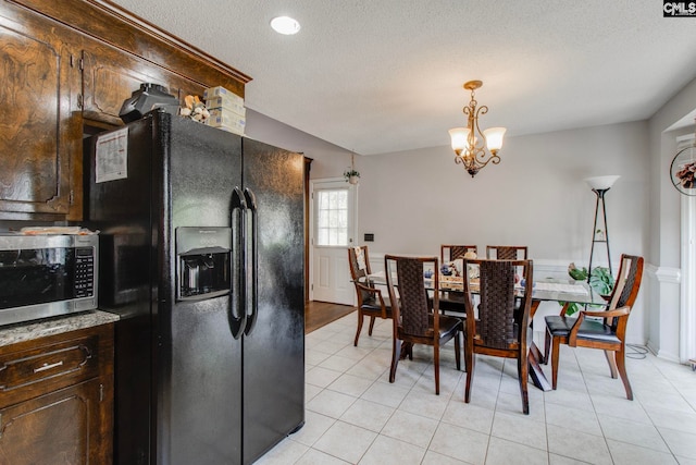 kitchen with dark brown cabinetry, a notable chandelier, light tile patterned floors, hanging light fixtures, and black fridge with ice dispenser