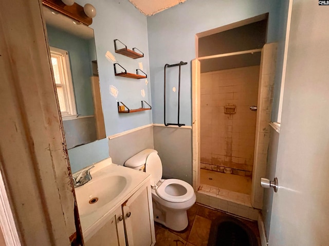 bathroom with toilet, vanity, tile patterned floors, and tiled shower