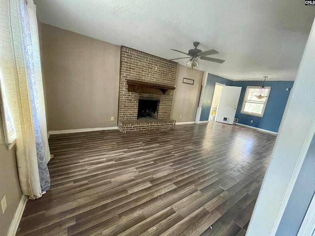 unfurnished living room featuring ceiling fan, dark hardwood / wood-style floors, a textured ceiling, and a brick fireplace