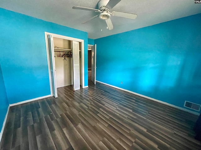 unfurnished bedroom with dark wood-type flooring, ceiling fan, a textured ceiling, and a closet