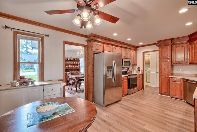 kitchen featuring crown molding, appliances with stainless steel finishes, washer / clothes dryer, ceiling fan, and light hardwood / wood-style flooring