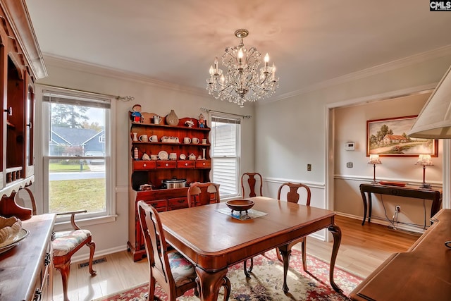 dining room with light wood-type flooring, a chandelier, and ornamental molding