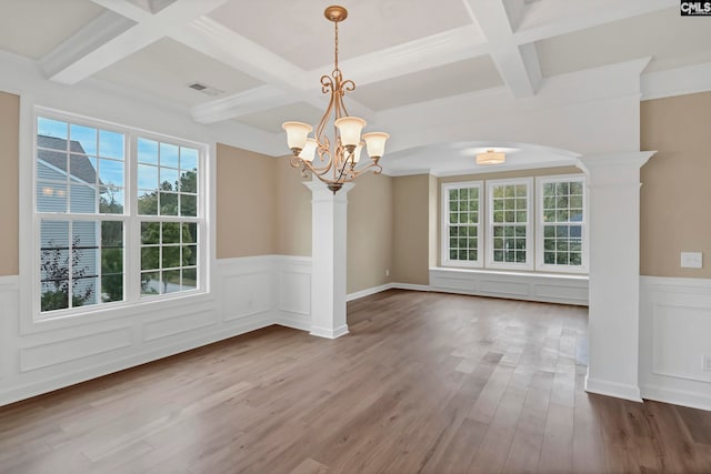 unfurnished dining area with beam ceiling, coffered ceiling, hardwood / wood-style floors, a notable chandelier, and ornate columns