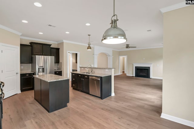 kitchen with light hardwood / wood-style flooring, sink, ornamental molding, pendant lighting, and appliances with stainless steel finishes