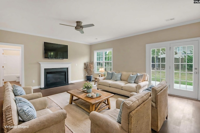 living room with a wealth of natural light, light hardwood / wood-style floors, and ornamental molding