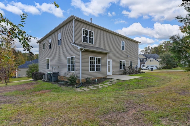 rear view of house featuring a garage, a lawn, and a patio