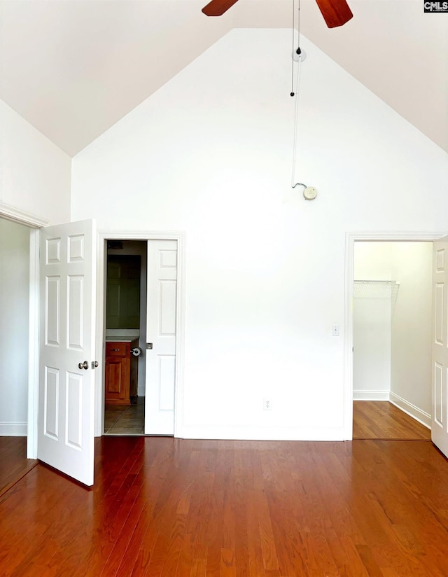 empty room with high vaulted ceiling, ceiling fan, and dark hardwood / wood-style floors