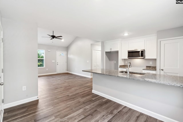 kitchen featuring ceiling fan, sink, light stone counters, vaulted ceiling, and white cabinets