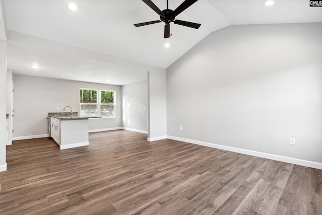 unfurnished living room featuring ceiling fan, hardwood / wood-style floors, vaulted ceiling, and sink