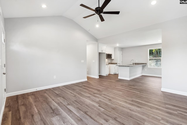 unfurnished living room featuring ceiling fan, wood-type flooring, sink, and lofted ceiling