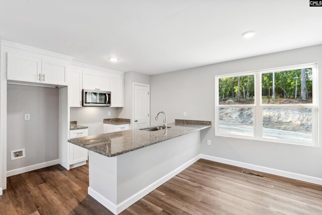 kitchen featuring white cabinetry, sink, dark hardwood / wood-style floors, kitchen peninsula, and dark stone counters