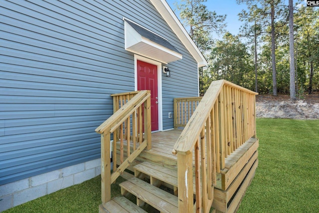 view of exterior entry featuring a lawn and a deck