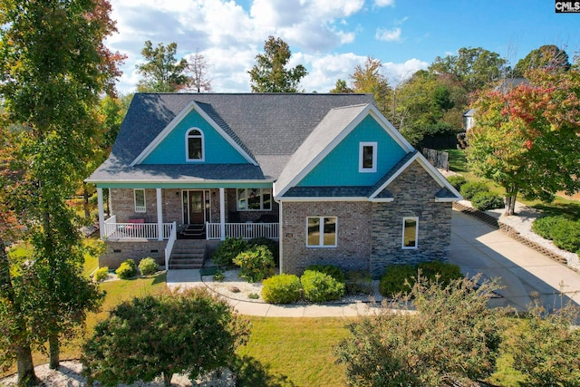 view of front of house with a porch, roof with shingles, crawl space, a front lawn, and brick siding