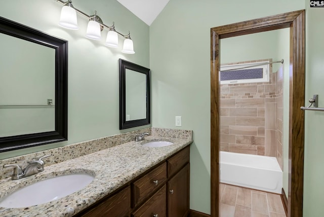 bathroom featuring lofted ceiling, vanity, and tiled shower / bath