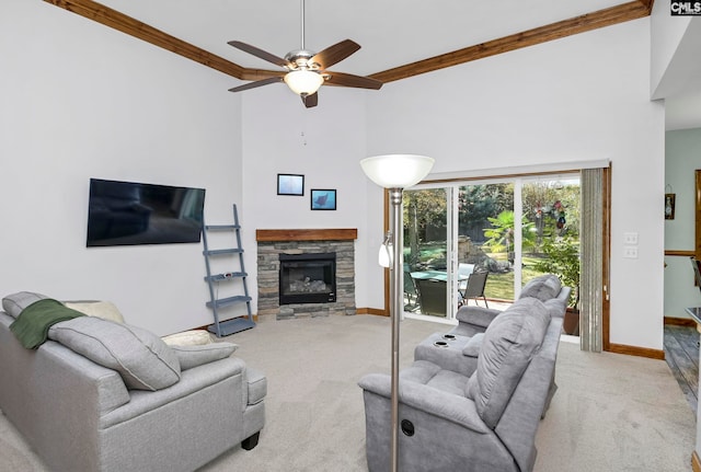 living room with a high ceiling, light carpet, ornamental molding, ceiling fan, and a fireplace