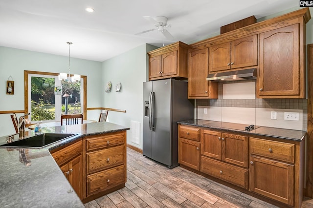 kitchen featuring pendant lighting, stainless steel refrigerator with ice dispenser, sink, black electric cooktop, and light hardwood / wood-style flooring