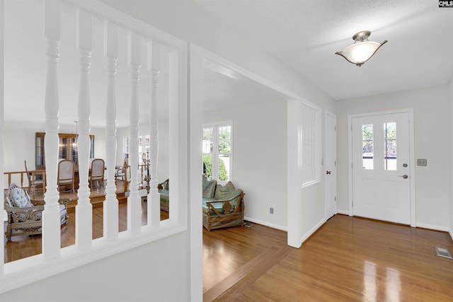 entrance foyer with a textured ceiling, wood-type flooring, and a healthy amount of sunlight