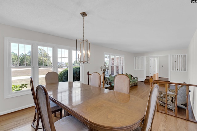 dining area featuring an inviting chandelier, a textured ceiling, and light wood-type flooring