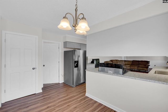 kitchen with gray cabinetry, pendant lighting, stainless steel refrigerator with ice dispenser, hardwood / wood-style floors, and kitchen peninsula