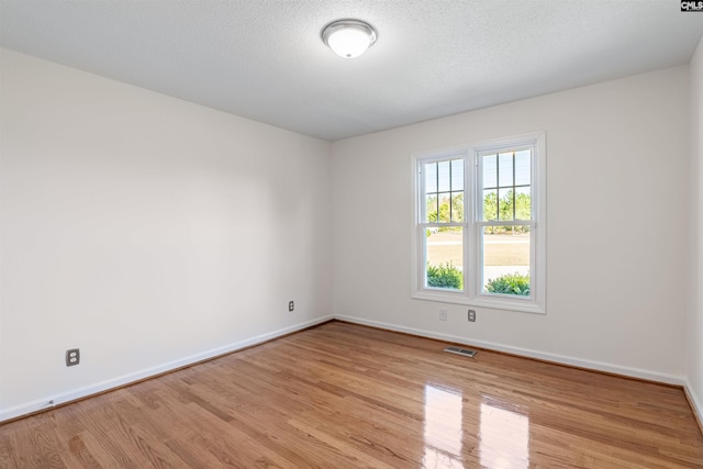 spare room with light wood-type flooring and a textured ceiling