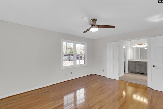 unfurnished bedroom featuring ensuite bathroom, light wood-type flooring, and ceiling fan