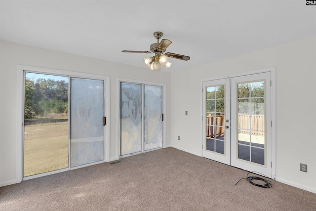 carpeted spare room featuring french doors and ceiling fan